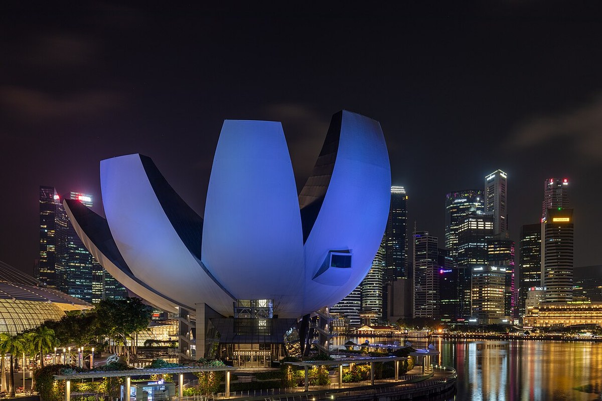 ArtScience Museum’s curved petals illuminated blue against the night sky and waterfront buildings.