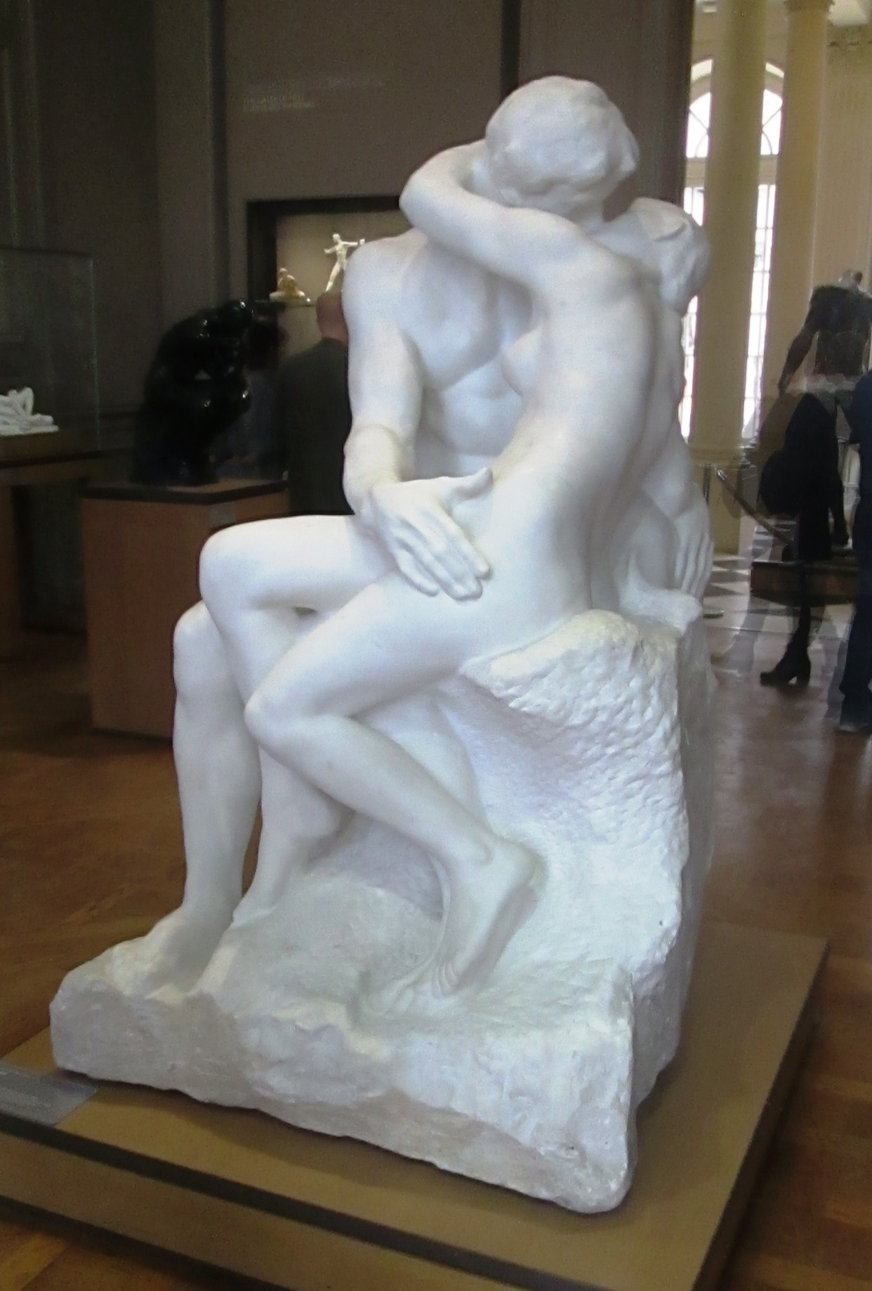 Two lovers turn towards one another in a marble embrace.