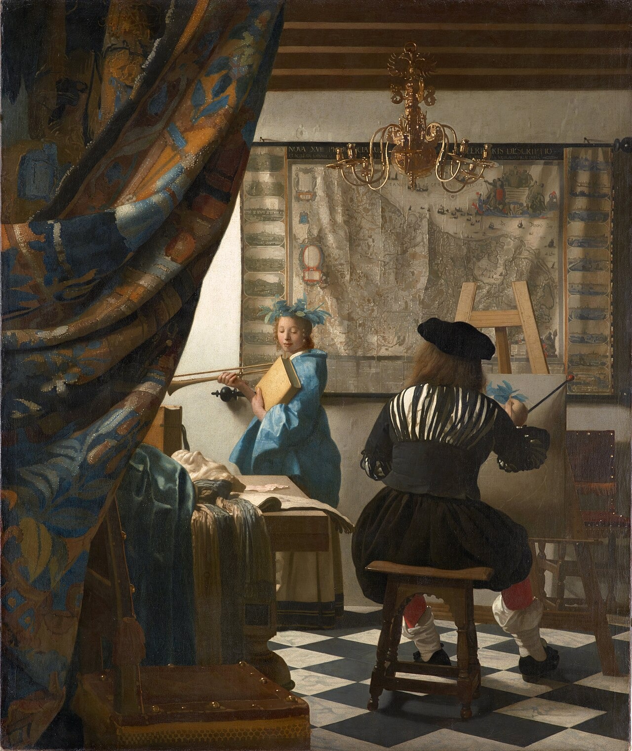 An artist seen from behind paints a woman in blue beside a wall map and a hanging chandelier.
