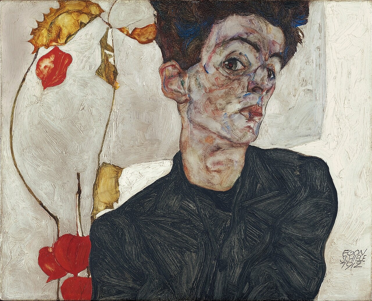 A slim man with tousled hair turns towards the viewer beside a branch with orange physalis fruits.