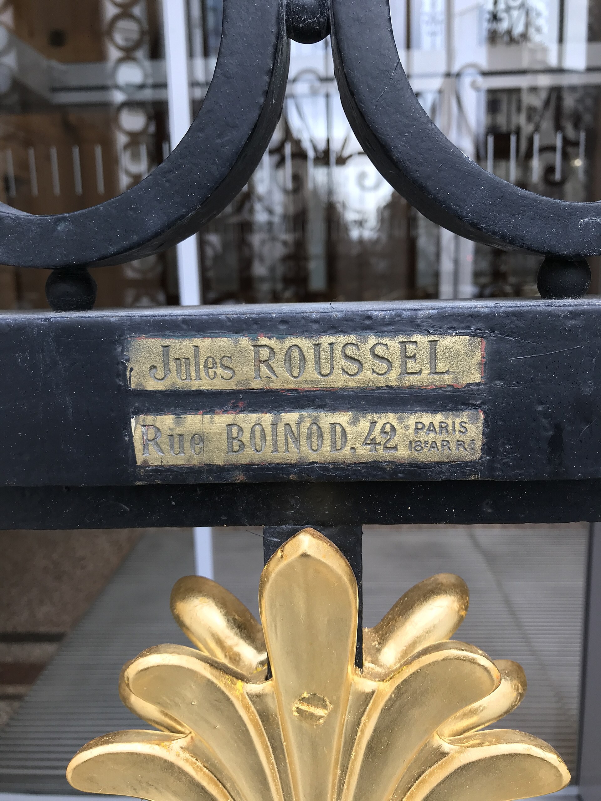A brass Jules Roussel maker’s plate and a gilded leaf motif ornament the Bourse de Commerce’s iron gate.