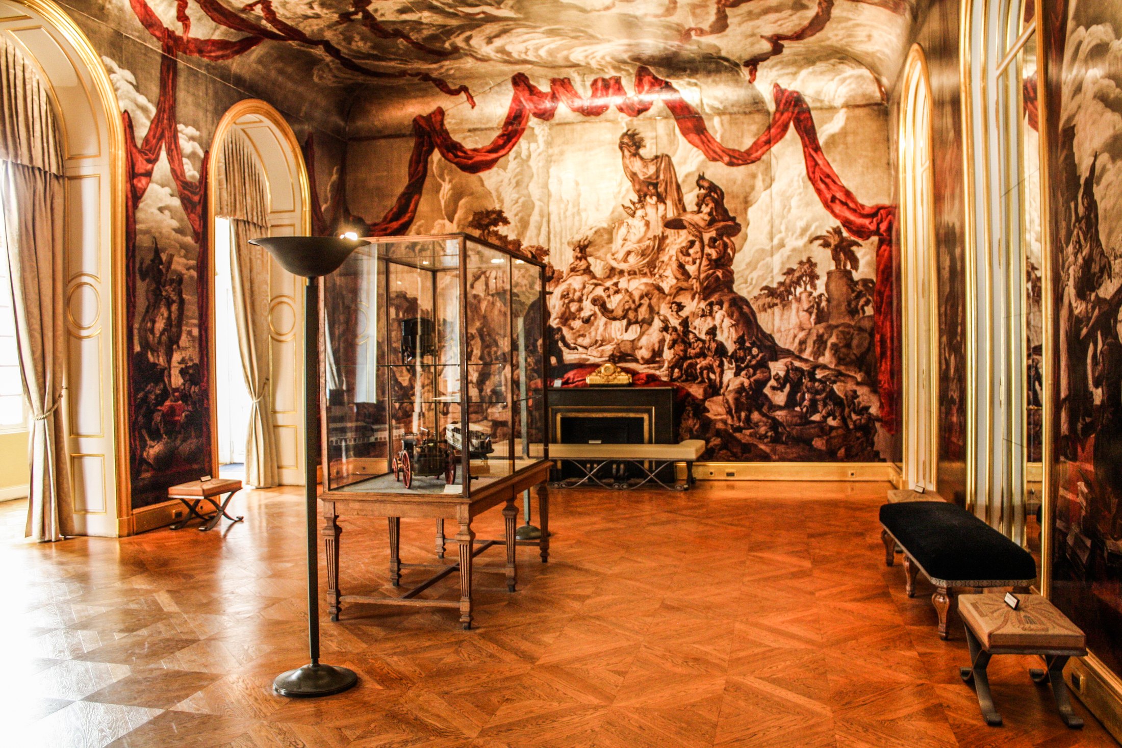 Sepia murals and painted red drapery cover the walls and ceiling of Carnavalet’s Wendel ballroom