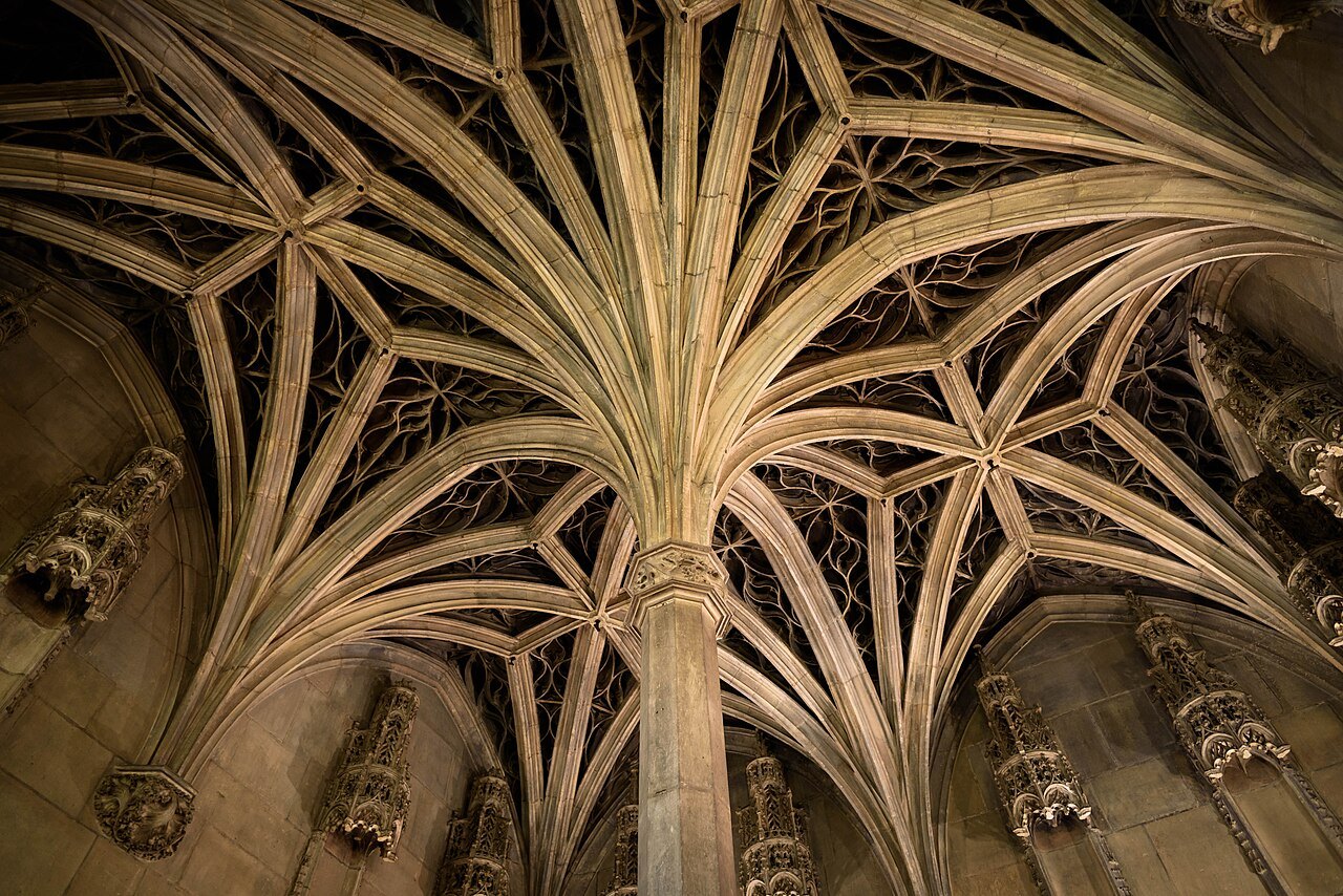 Intricate branching stone ribs across the vaulted ceiling of the Hôtel de Cluny chapel.