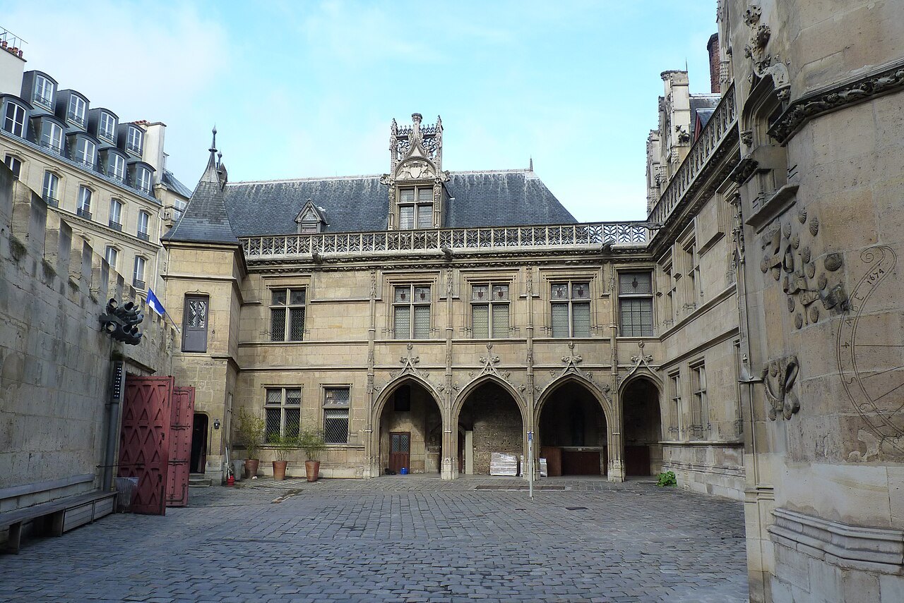 Gothic stone façades and arched doorways around the cobbled courtyard at the Musée de Cluny.