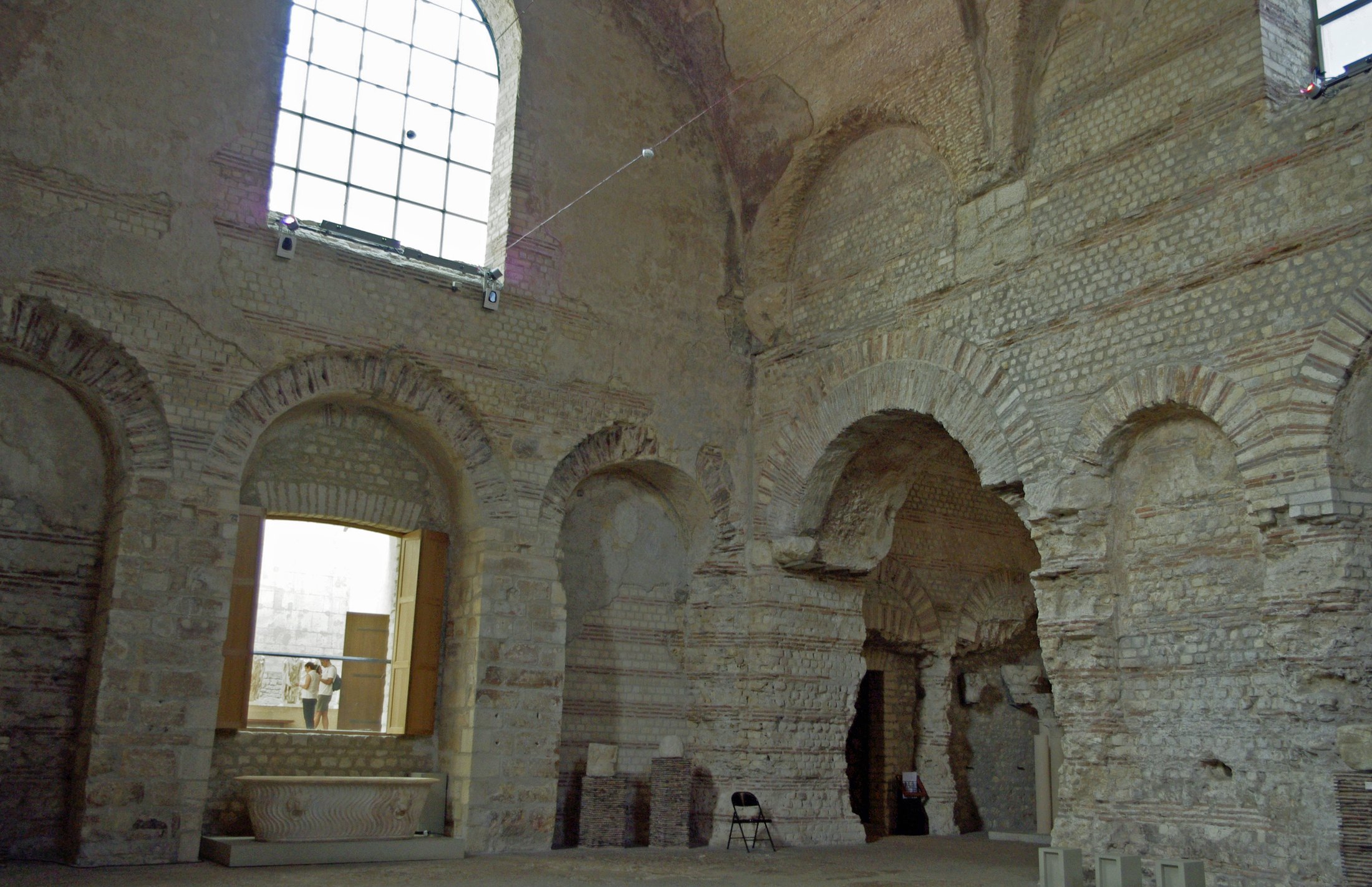 Tall ancient stone walls, arches and windows in the Roman baths at the Musée de Cluny.