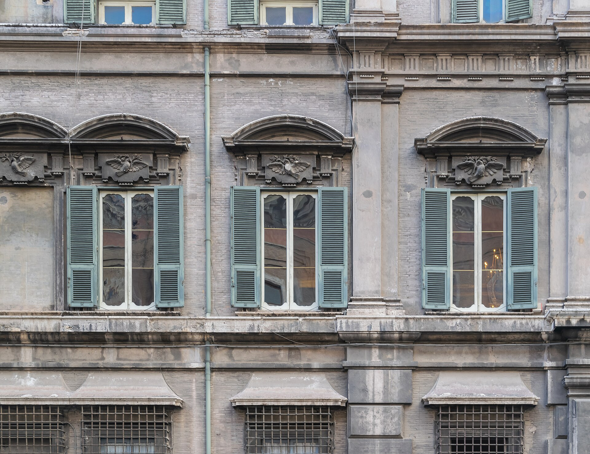 Three shuttered windows and carved stone pediments on Palazzo Doria Pamphilj