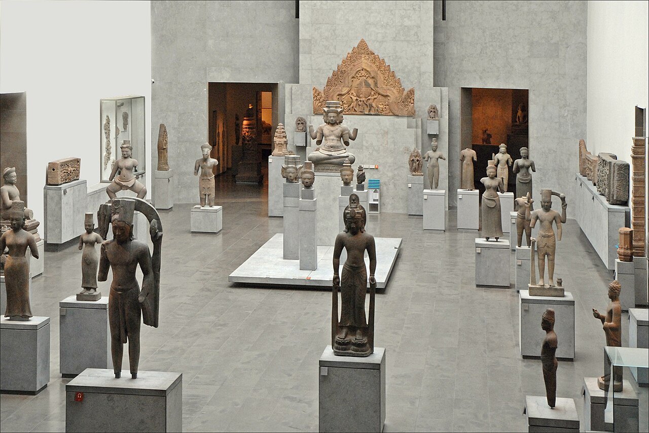 Rows of ancient stone Khmer figures and carved temple fragments in a Musée Guimet gallery.
