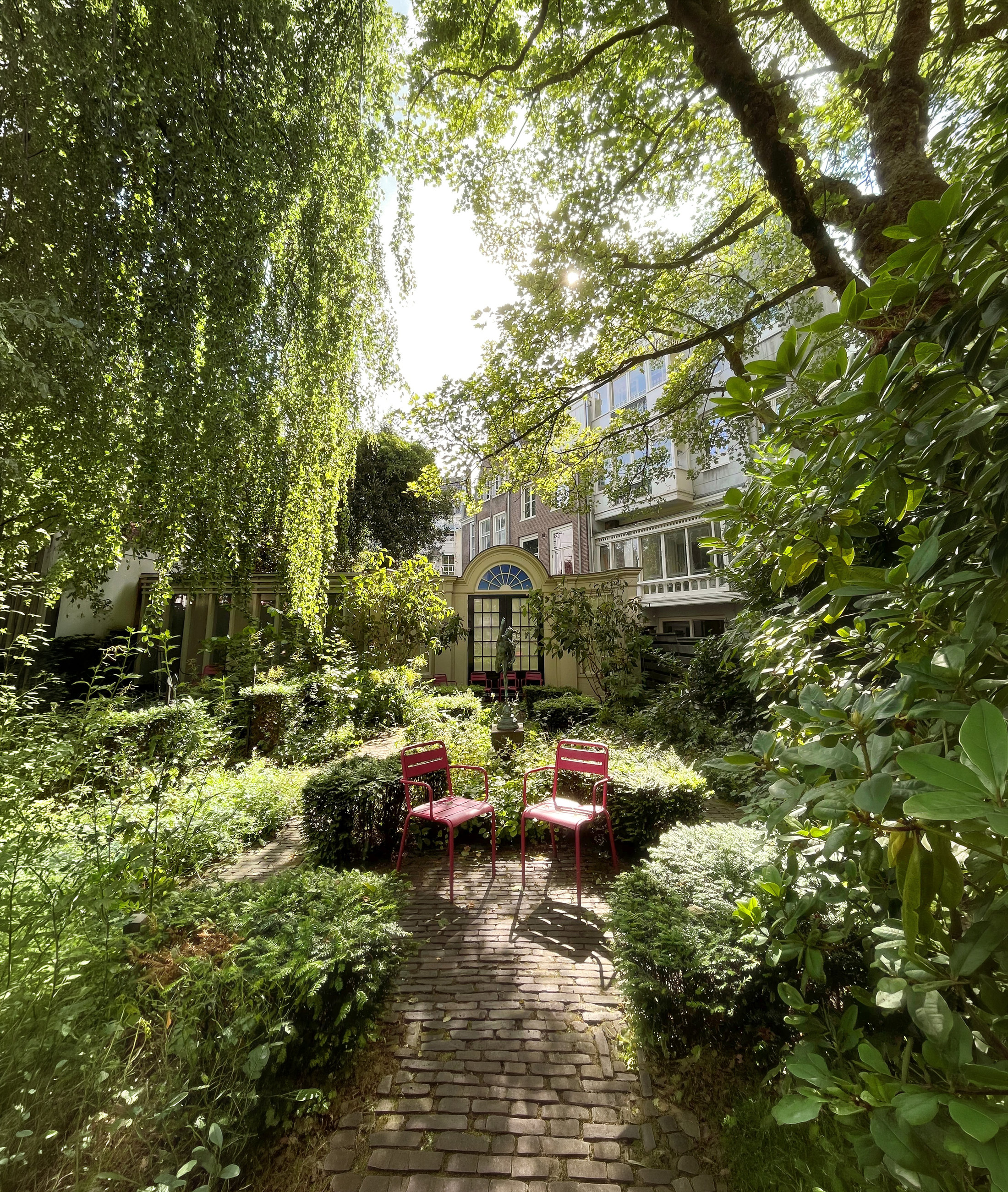 Leafy canal-house garden and brick path behind Huis Marseille
