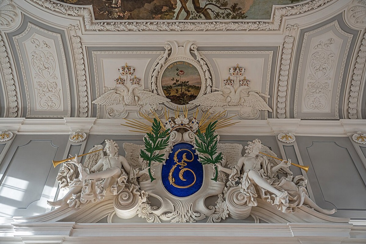 White ornamental figures and a gilded imperial monogram in Kadriorg Palace.
