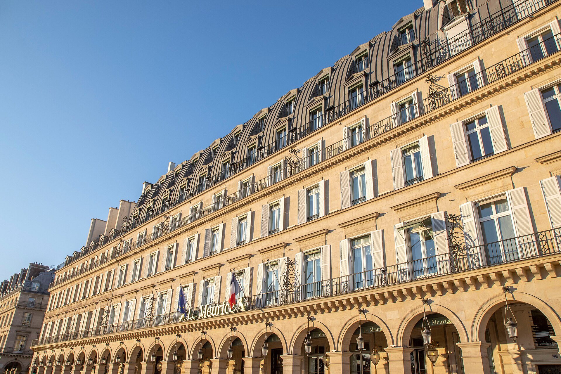 The arcaded rue de Rivoli facade of Le Meurice, with flags above the entrance.