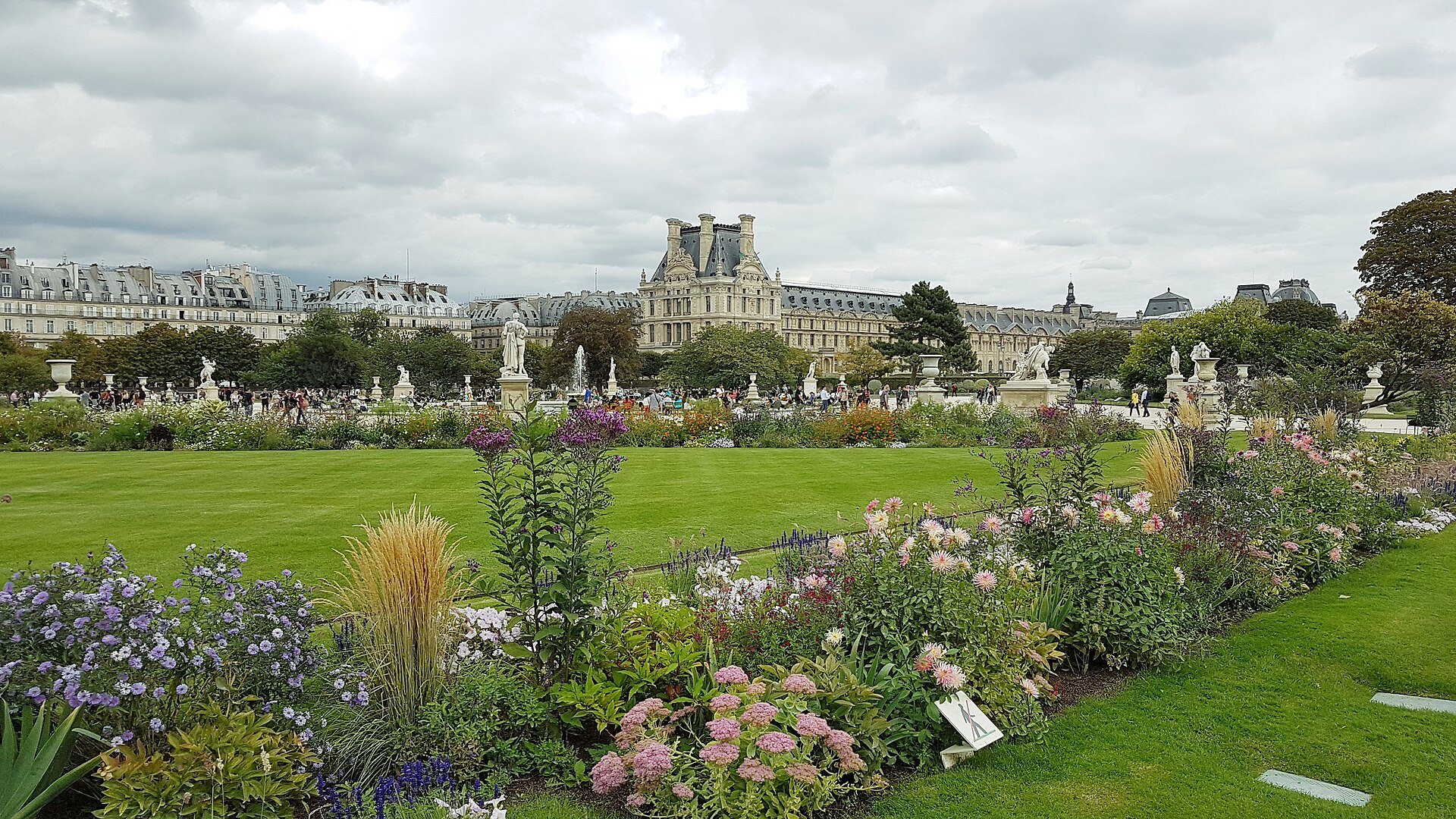 Flower beds in the Jardin des Tuileries with the Louvre palace behind them.