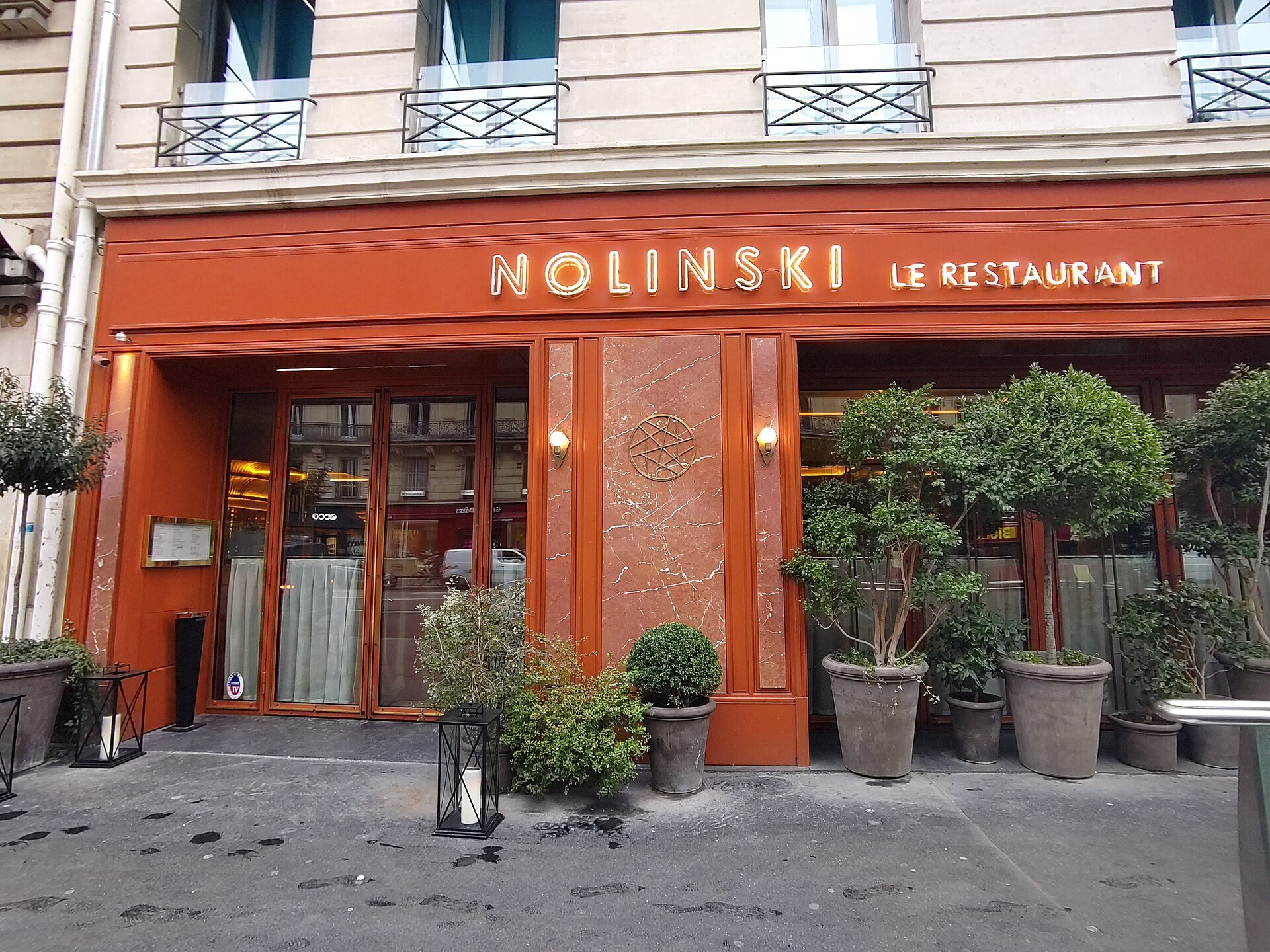 The orange-red ground-floor frontage of Nolinski Paris on avenue de l’Opéra.