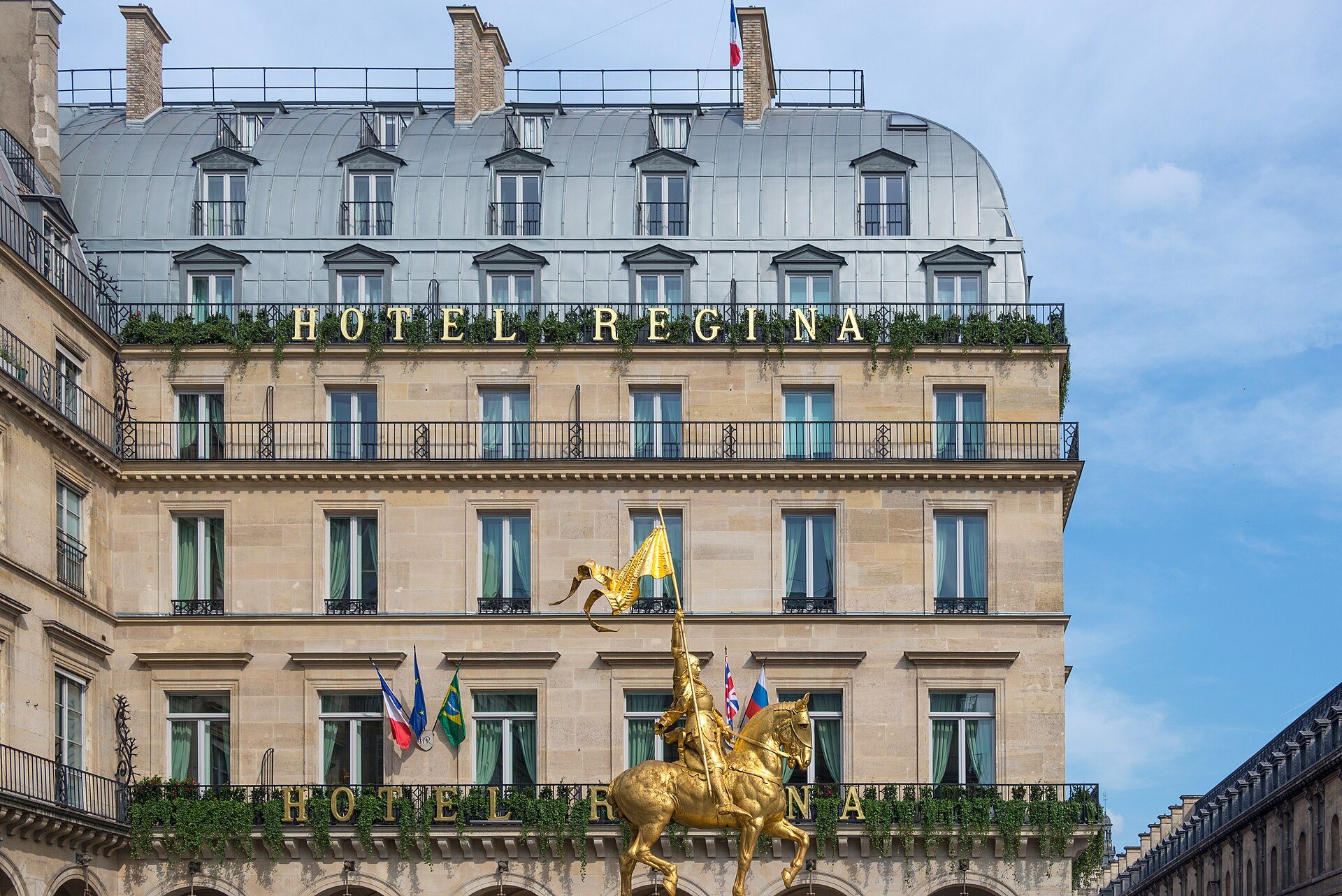 The Hôtel Regina facade on Place des Pyramides, with the gilded Joan of Arc statue in front.