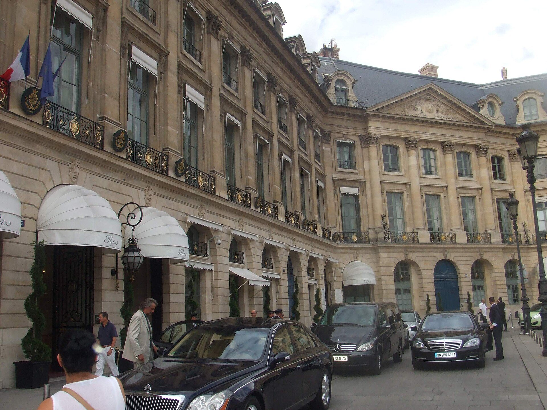 The Ritz Paris entrance on Place Vendôme, with awnings and cars outside.