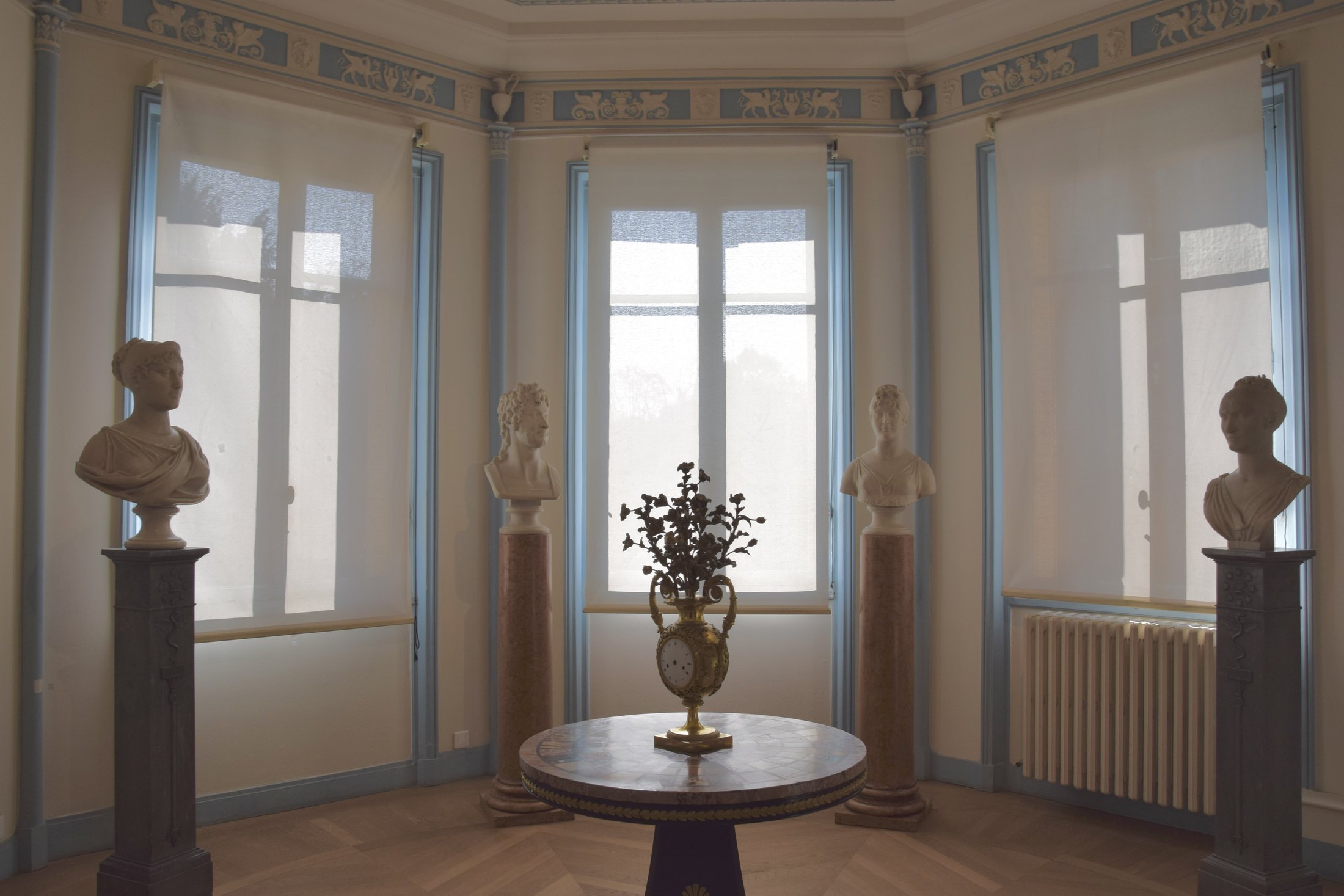 Marble portrait busts and a gilt clock in a pale-blue Empire salon at Musée Marmottan Monet