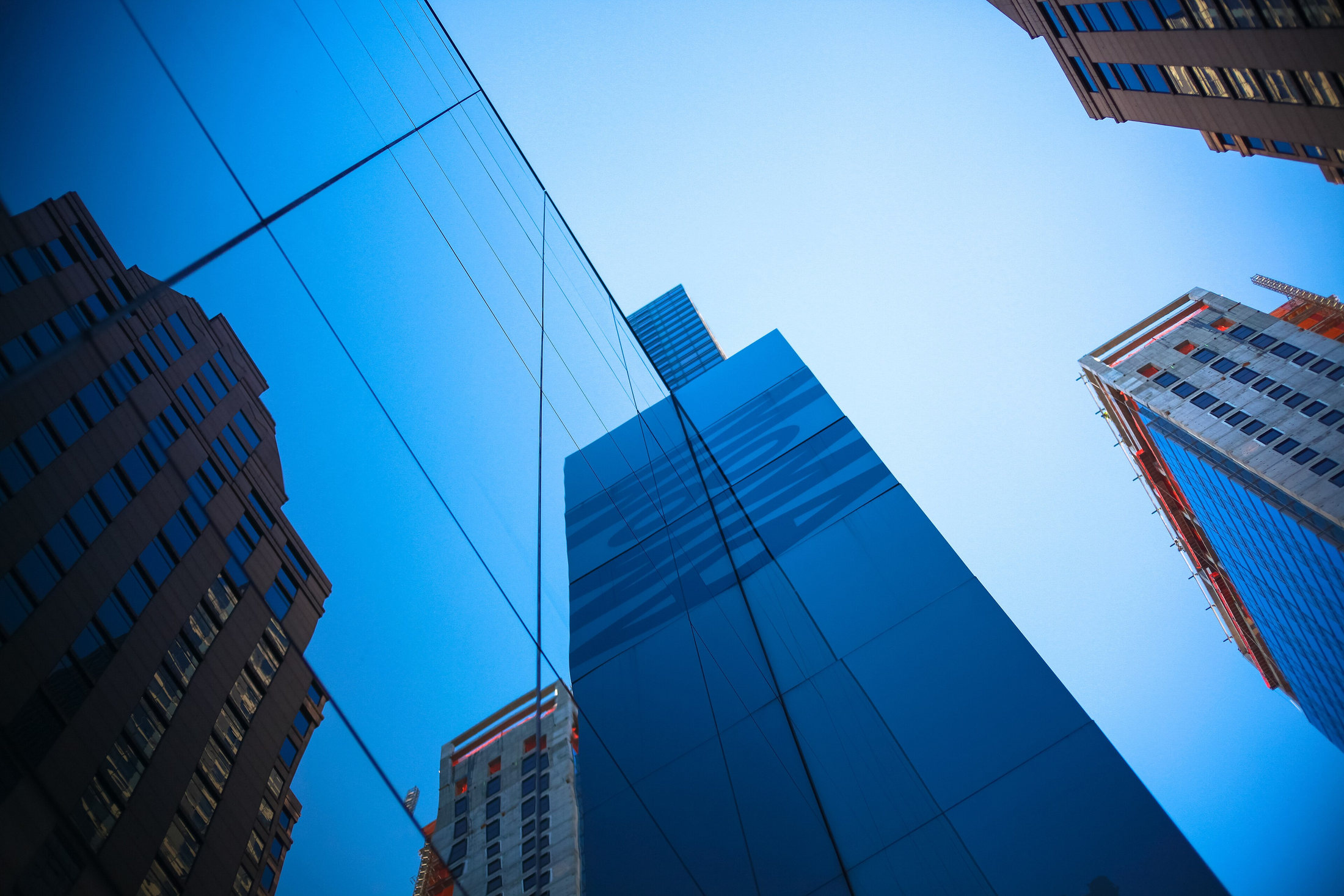 Midtown buildings reflected in MoMA’s blue glass façade