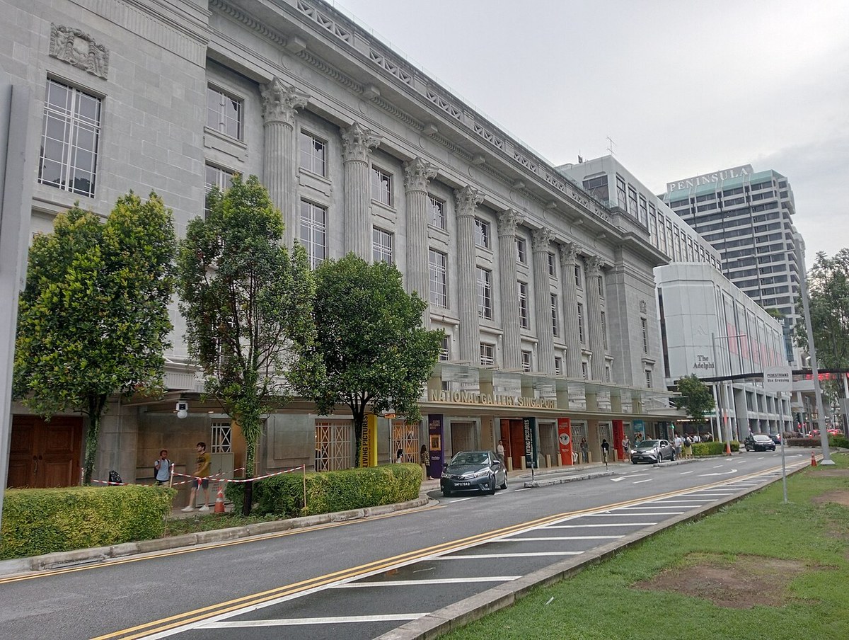 National Gallery Singapore’s long stone facade beside a tree-lined city street.