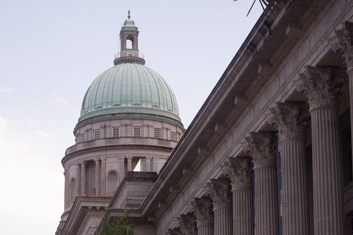 Green dome of the former Supreme Court rising behind stone Corinthian columns.