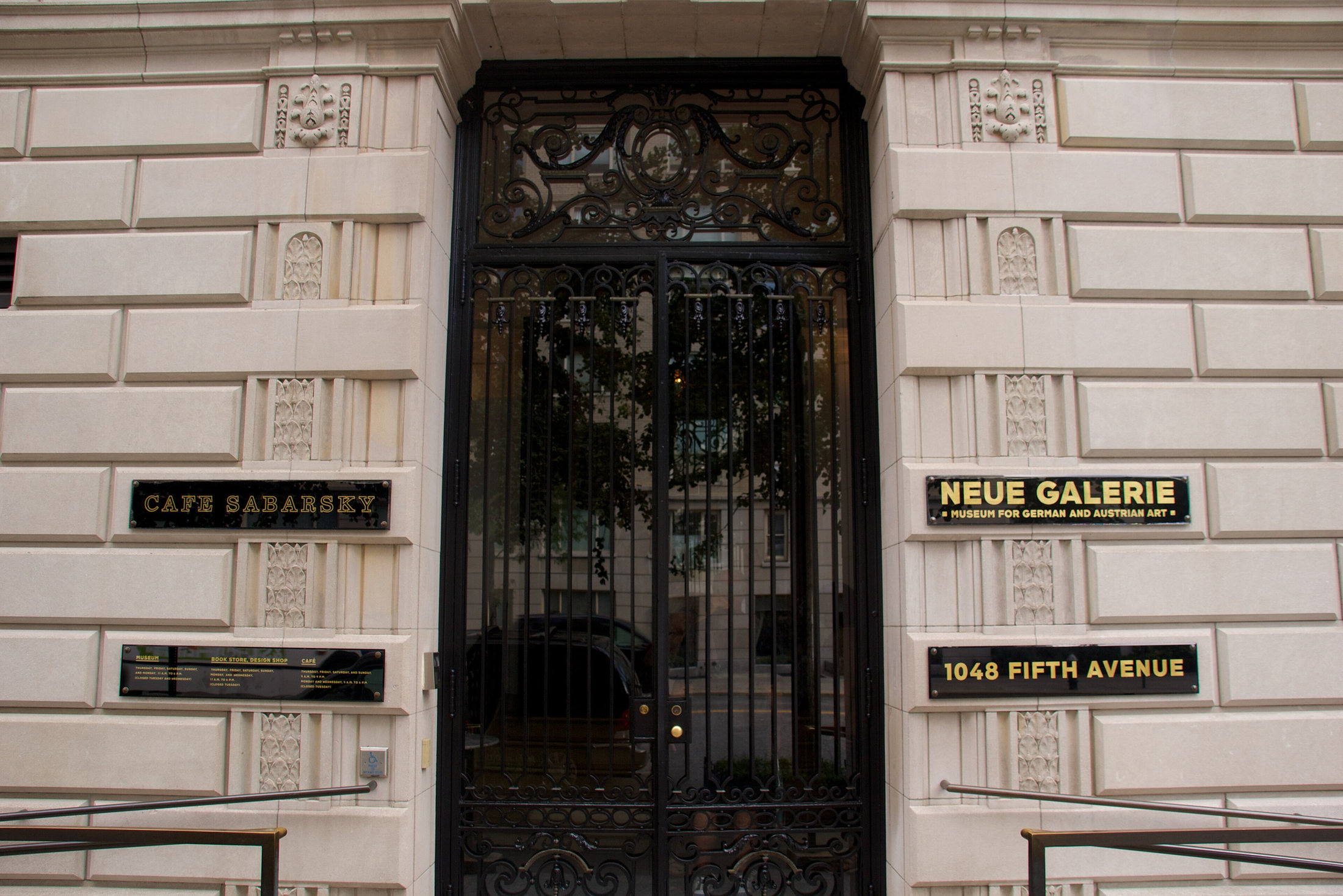 Ornate iron entrance doors at Neue Galerie with the museum and Café Sabarsky nameplates