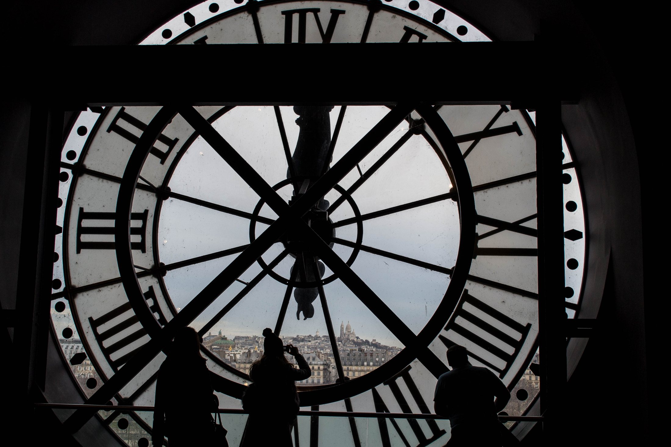 Silhouetted visitors beside the large clock face inside Musée d’Orsay
