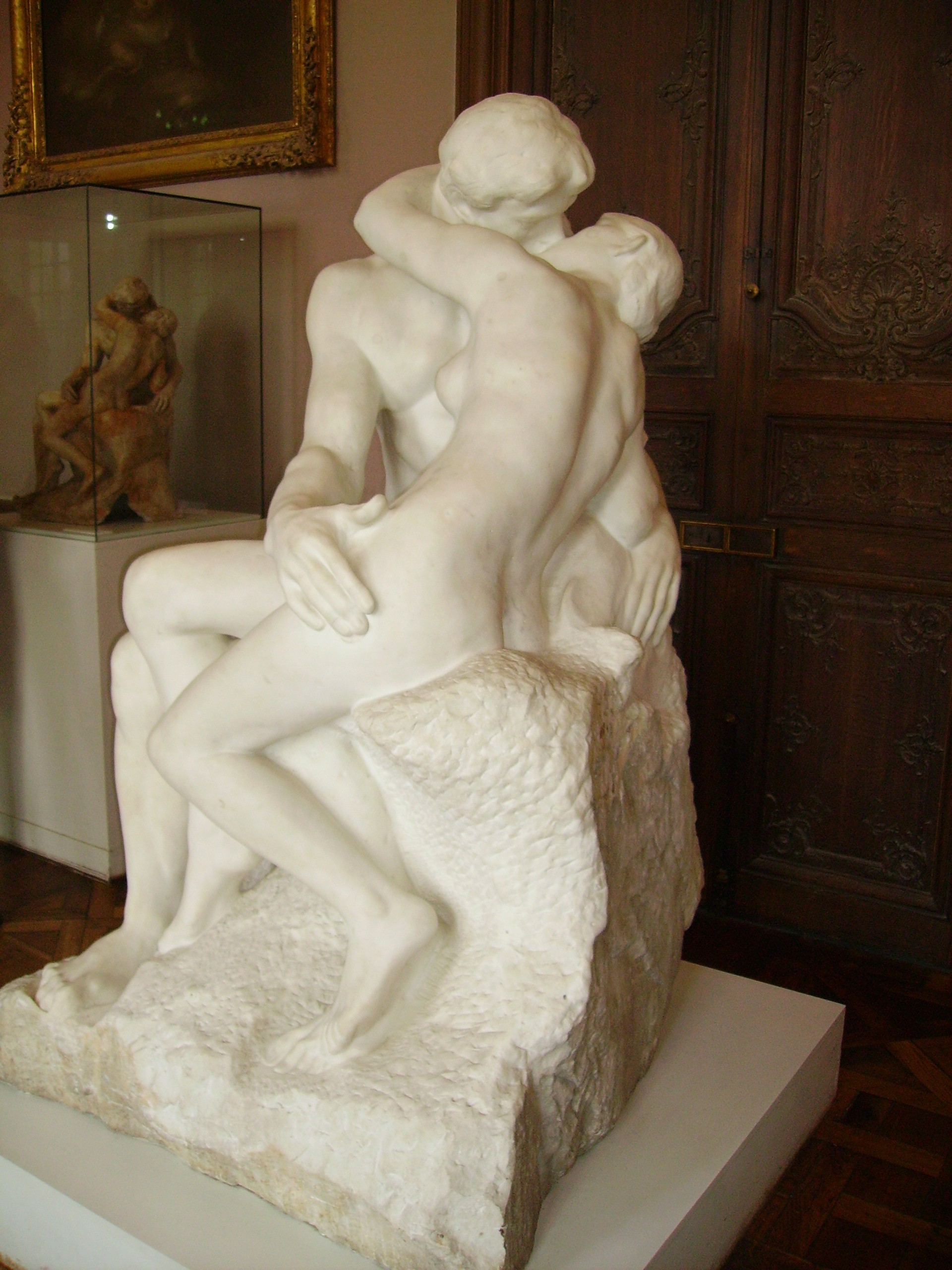 Two seated figures embrace in Rodin’s marble sculpture The Kiss inside the Musée Rodin.