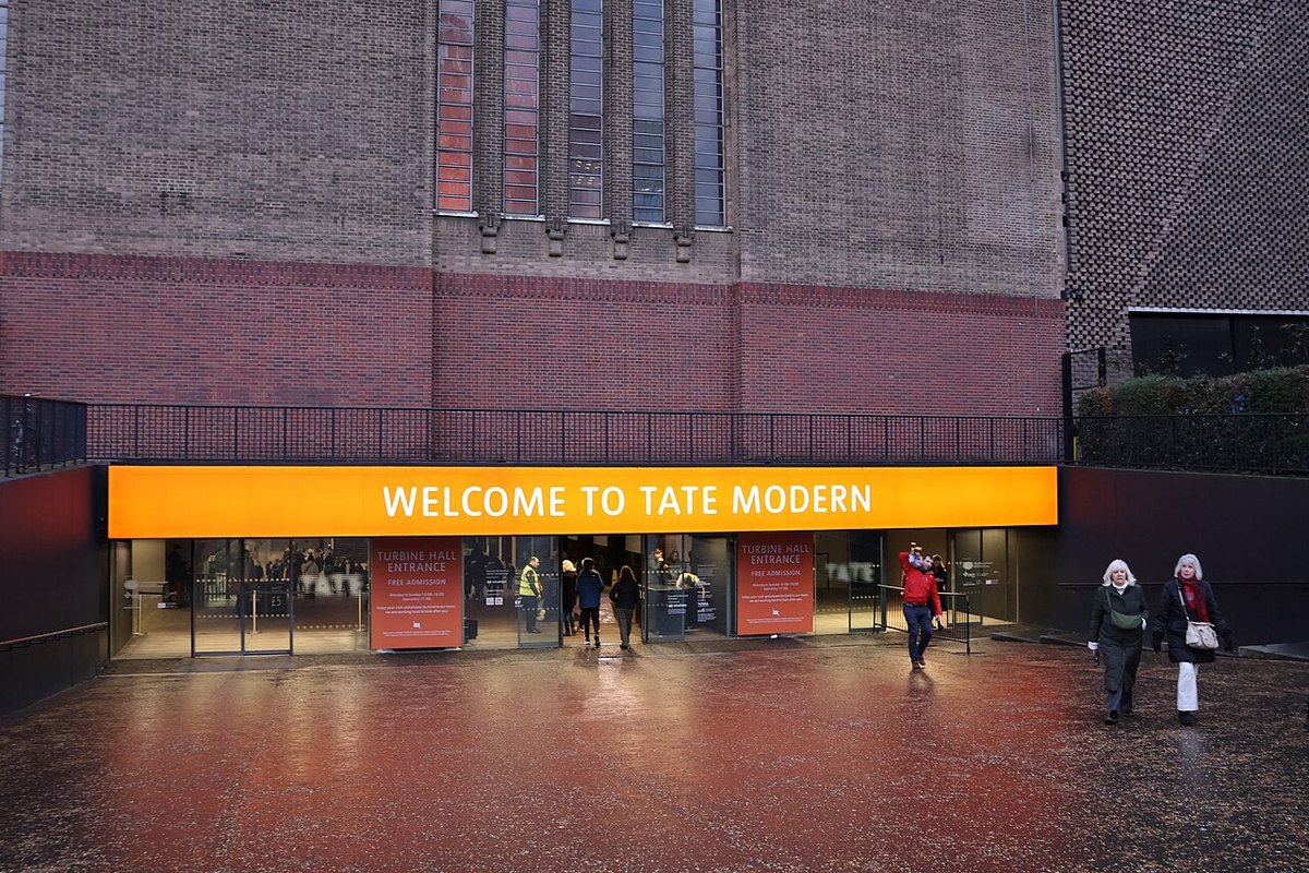 The Tate Modern entrance beneath a brightly coloured welcome sign.